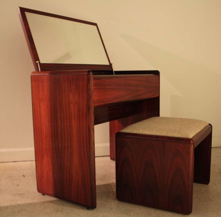 Danish modern rosewood vanity and matching bench with original fabric in unused condition.  Top lifts up to reveal a mirror and storage compartment.  Seat cushion is oatmeal tweed.  Gorgeous wood grain throughout.