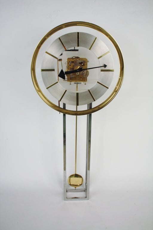 Vintage modern pendulum wall clock by Howard Miller on brass, brushed steel, lucite and chrome.  Front key (included) mechanism operates lovely chime and pendulum swing protected by a chrome cage.  All clock works are exposed through a clean, clear