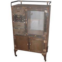 Dental cabinet of weathered steel on wheels with drawers and glass-panel door