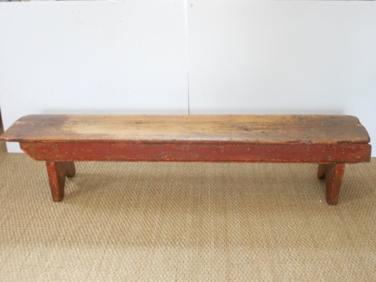 Primitive pine boot bench in as-found paint colors sealed with wax to soften edges and wear in the wood. Very sturdy and wonderfully worn from more than a century of boots going on and off. Projects  its own primitive style in the v-cut legs and