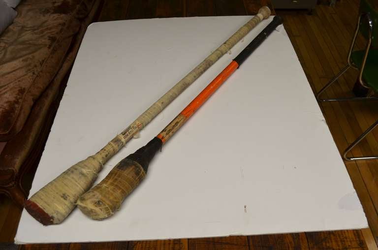 Pair of Canadian broom ball sticks. Scarred, bruised, bandaged and battle tested. Nice contrast of colors: one worn white, the other black with a color stripe. We like to think of them as Quidditch brooms. They may not fly but they sure have flown