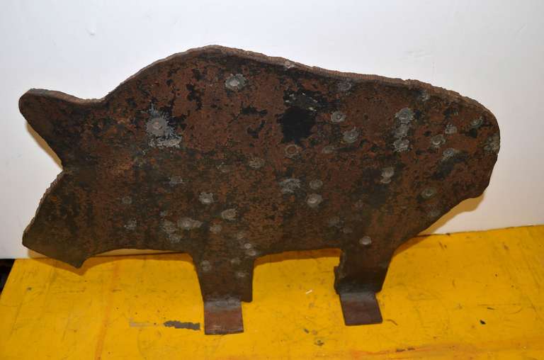 Cast iron, carnival target of a hog has taken some hits, for sure. Held up just fine, made of solid, half-inch thick, roughhewn cast iron. Love the patina: the dings, divots, tactile rusty coat. Stands securely on square feet (4.5