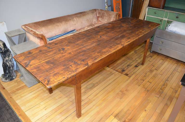 Early 20th century pine table from midwestern mercantile shop. The legs of this 8-foot long beauty fold under for easy transport. Wonderful wood grain and worn patina of the top has been cleaned and sealed to resist moisture and scratching. Stands