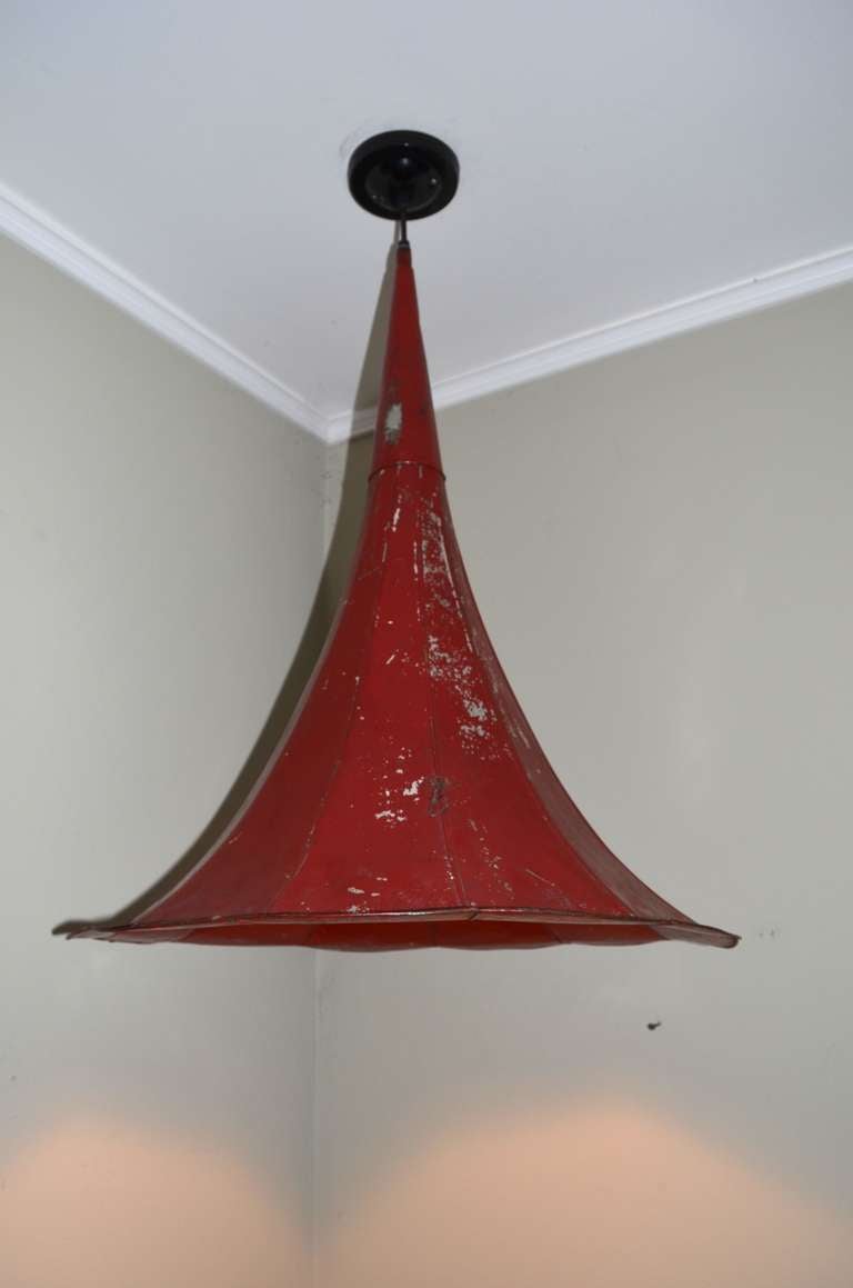 Antique, as-found red-painted gramophone horn as dramatic ceiling pendant spotlight. For dining room, sitting area, ambient corner, this horn pendant light projects a broad circle of light on people and objects below. Change the bulb within to vary