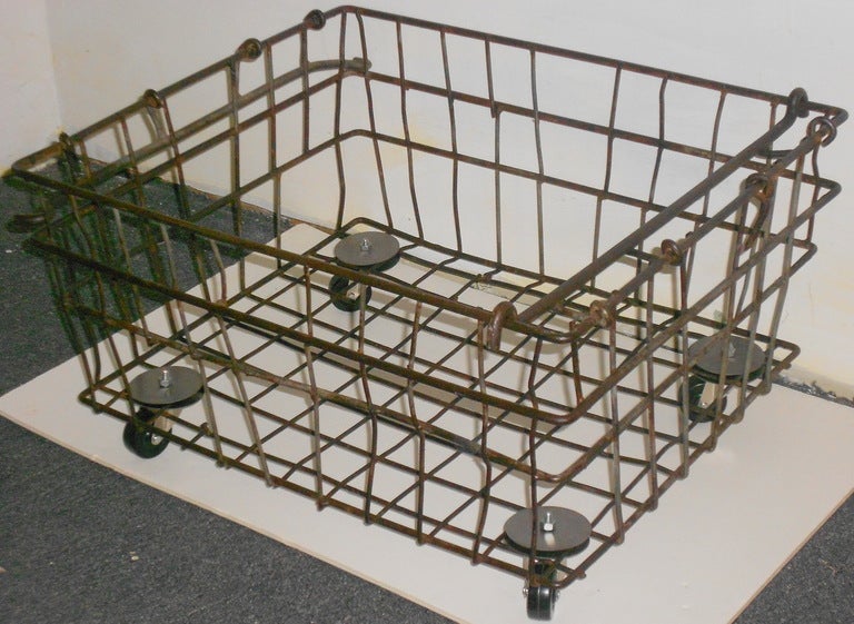 Industrial, steel wire basket on wheels with collapsible handles. These were used as oyster baskets on commercial fishing boats.  Basket has been cleaned and sealed for use indoor or out. Its pivoting, hard rubber wheels and easy drainage make it