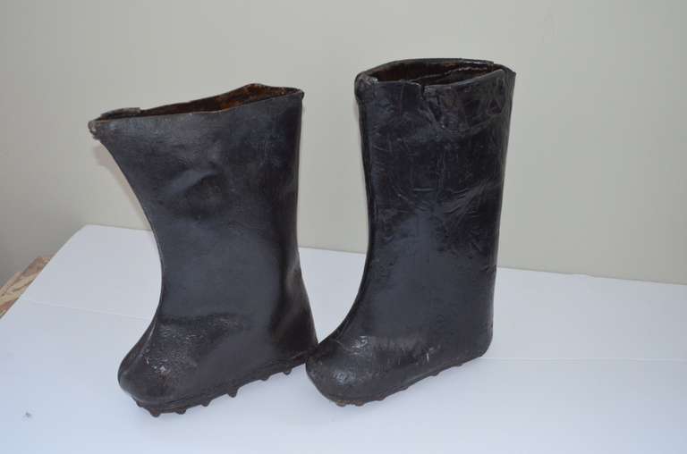 Wonderful pair of antique Chinese rice paddy work boots. Boots are made of lacquered leather and are mighty stiff. The bottom of the boots have knobbed metal bits for added traction. Striking as conversation piece and as a piece of sculpture.