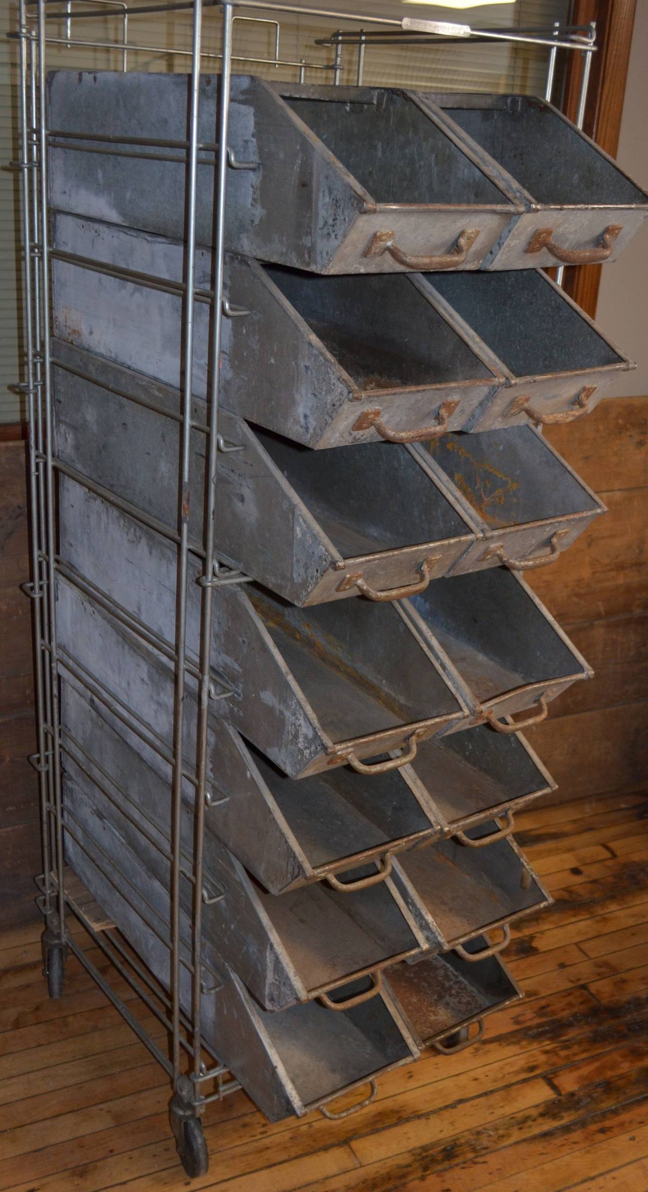 Industrial bakery rack with 14 slide-out bins from Wonder Bread Bakery. That's the bread us baby boomers grew up on slathered with peanut butter and jelly. This steel rack is mounted on pivoting wheels for easy mobility. Each of the 14 galvanized