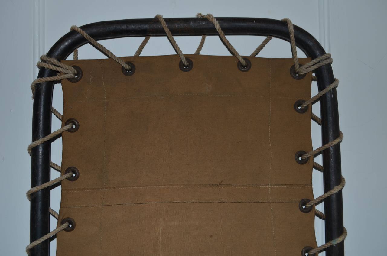 Canvas cot was used aboard ship. May have been for emergency transport of injured sailors. Has such an intriguing sculptural design: the curved frame supporting the weave of the rope through the grommeted canvas in a rich light brown chocolate color