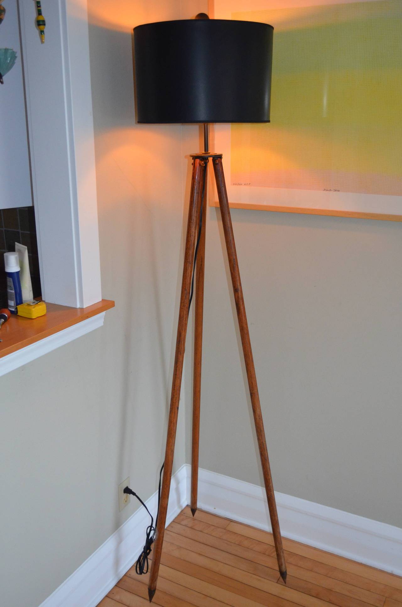 Surveyor tripod by David White has been made into a slender, sophisticated floor lamp. Legs of oak tipped with steel. Professionally wired with UL-approved components including 10-foot black cord, 3-way socket (150 watt maximum), 8