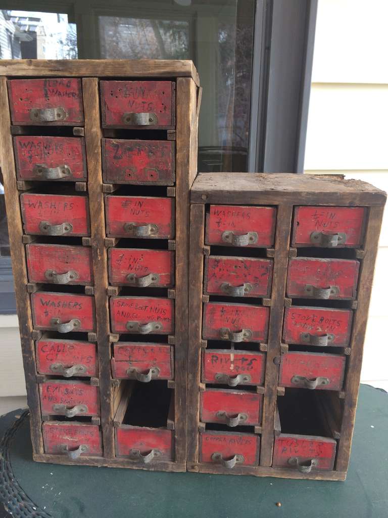 Hardware cabinet of hand-hewn wooden drawers displays wonderfully faded red-paint facade with steel pulls. Was once home for all variety of small hardware accessories, nuts, screws, rivets, washers, etc., each drawer marked as such in hand-written