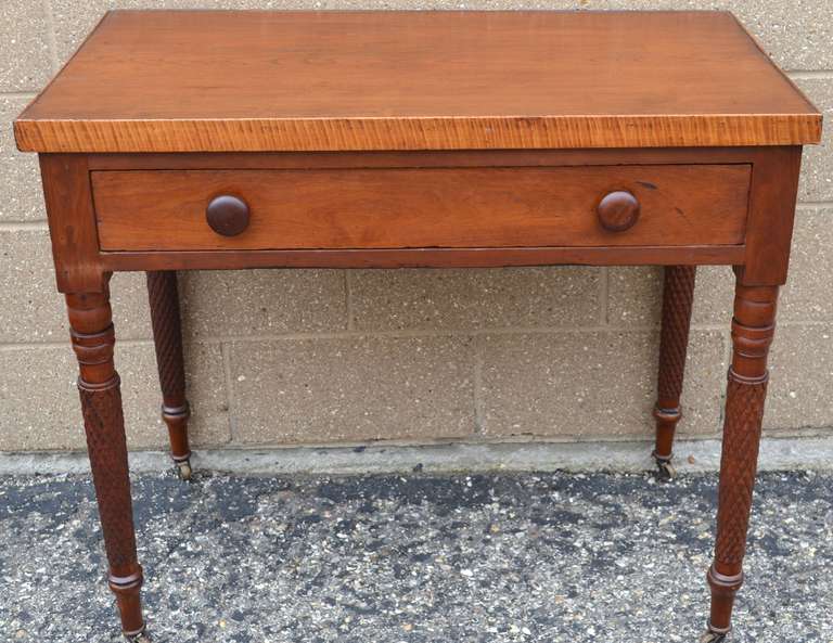 Sheraton table with tiger maple surround and pineapple turnings on legs mounted on casters. Measures 23.25