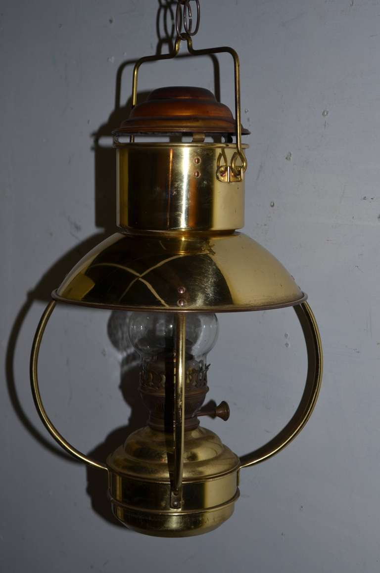 Mid-century, two-toned copper lantern. Illuminated by lamp oil, this lantern casts a rich, warm glow bright enough to read by or wonderfully ambient on lower intensity. Ideal for summer porch living with its hanging chain and protected hurricane