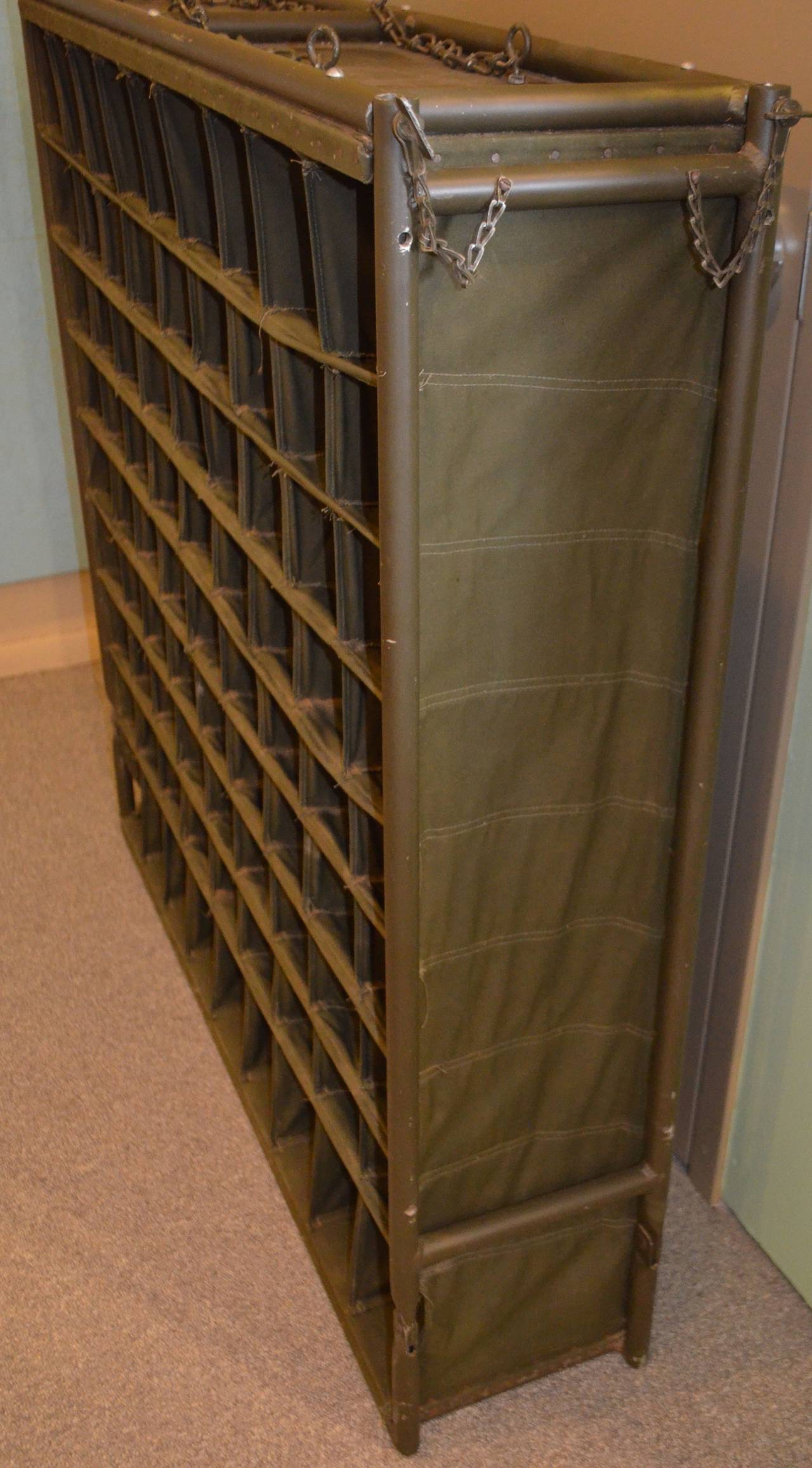 U.S. Army field postal unit is made of canvas stretched on steel rods with hanging chains. Consists of 81 canvas postal cubbies and was designed as a mobile postal unit for field use. Lightweight, portable and easily suspended in a tent, this unit