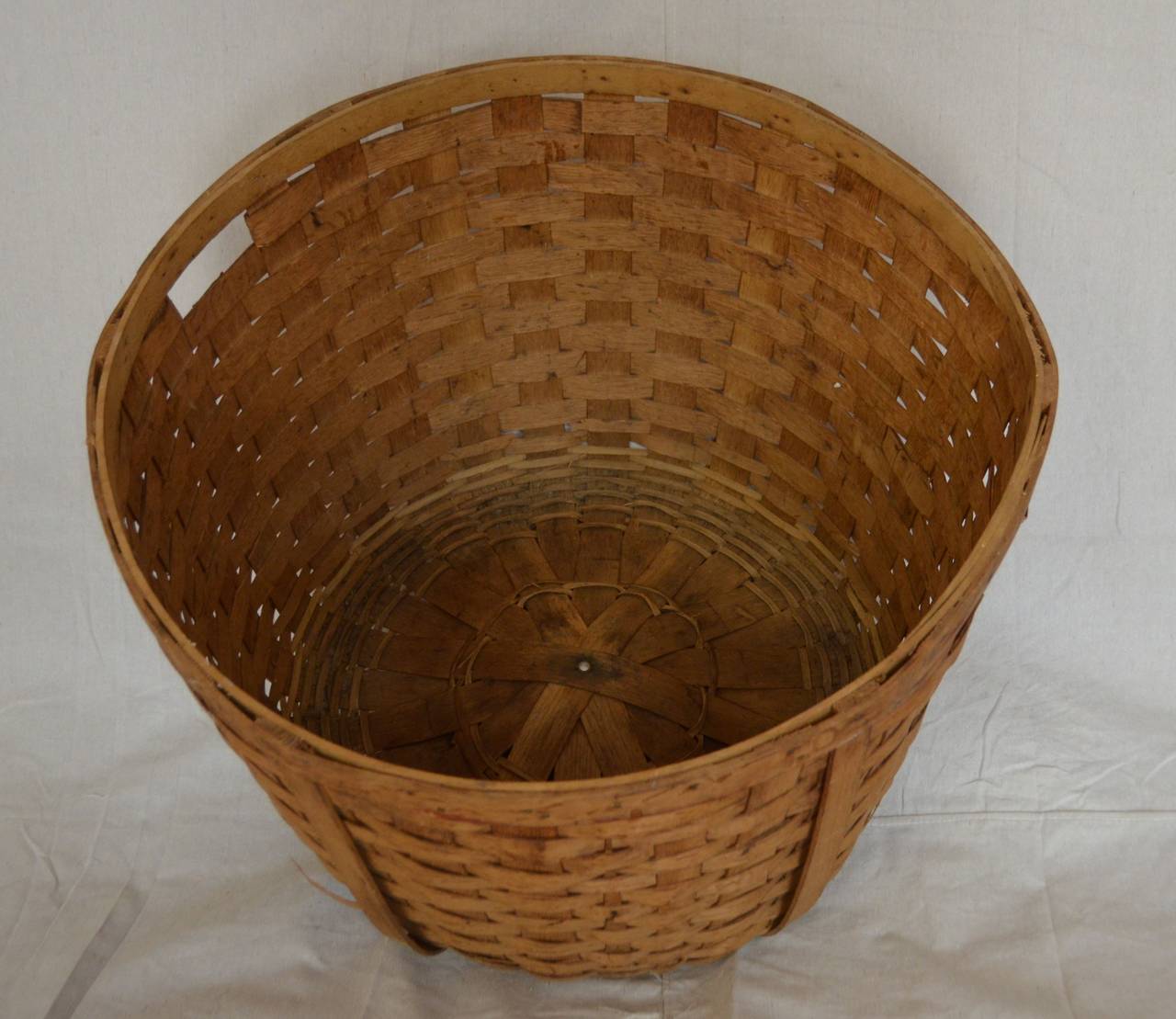 Large-size, round vintage basket of woven wooden slats and cut-out handles.  Aesthetically-pleasing circular design in soft, honey-colored hues provides versatile storage capacity in bedroom, bath, laundry room, for kids' room toys.