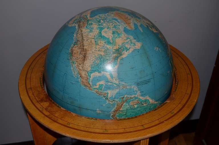 Mid-century globe on wooden stand calibrated for time zones. Lower shelf provides storage for books, magazines and the like. As we've been swallowed up by the digital era, tangible, tactile globes and maps have become quaint artifacts from the past.