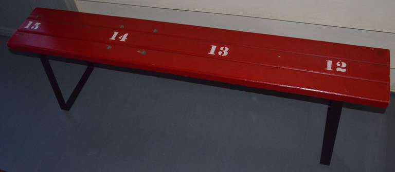 Fiery red bench on steel bracket legs made from vintage bleacher seat section out of mid-western University field house. Numbered 12-15.