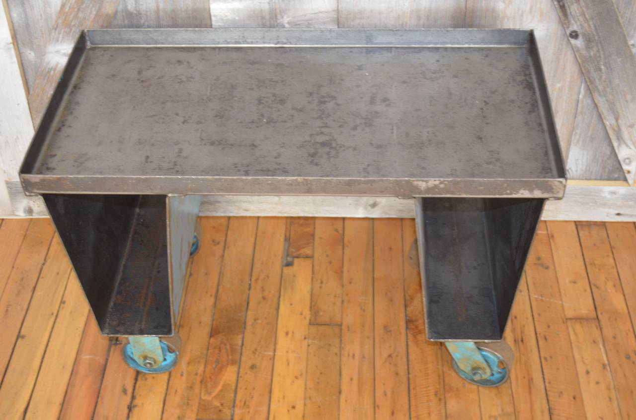 Industrial steel factory cart on wheels with original blue paint has been thoroughly cleaned and lacquer sealed. Talk about multi-functionality. This neatly-sized piece makes an ideal end table, side table or higher coffee table with storage slots