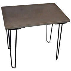 Table of solid concrete mounted on hairpin legs.