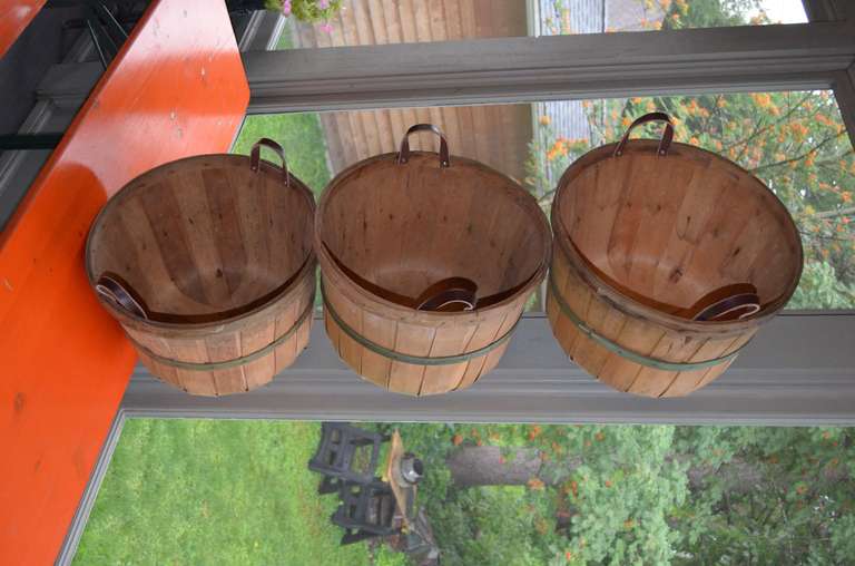 Priced individually at $25 each. Several hundred available. Inquire about shipping discount on multiples. Wooden slat, apple bushel baskets with added rich brown leather handles. Hailing from the 1930s, these baskets were found in the barn of a