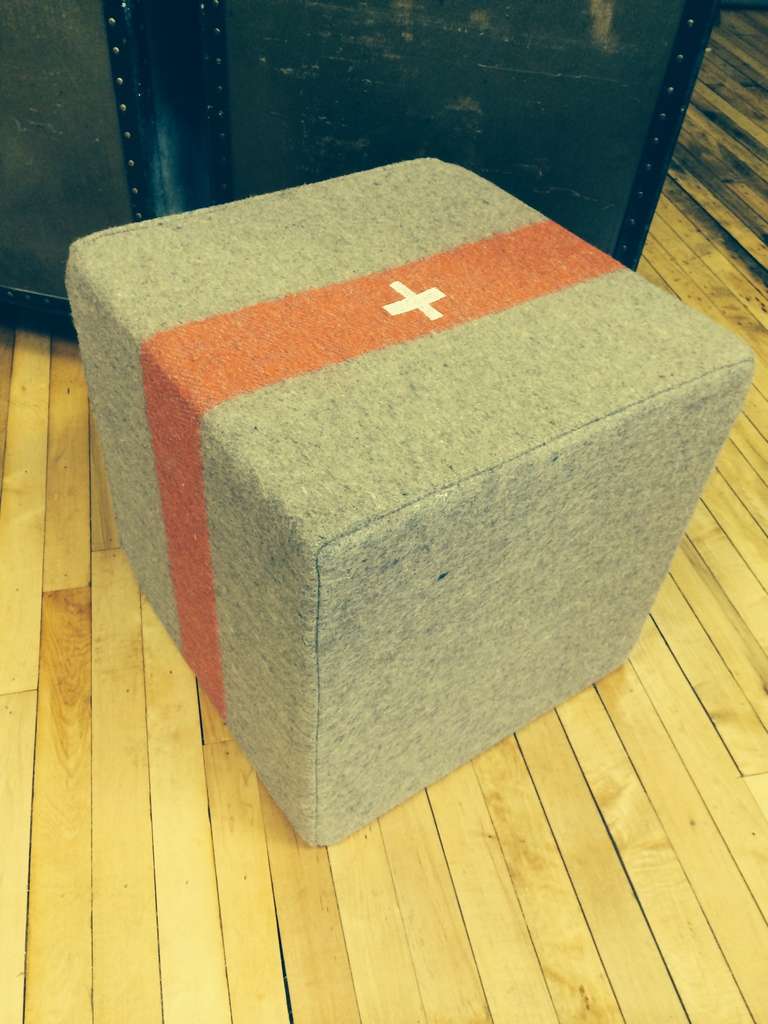 Swiss Army Blanket of wool dating back to WWII has been transformed into  multi-functional object as pouf, ottoman, footstool, seat. This blanket, discovered after the war from new/old stock, was originally woven for relief of the wounded, but never