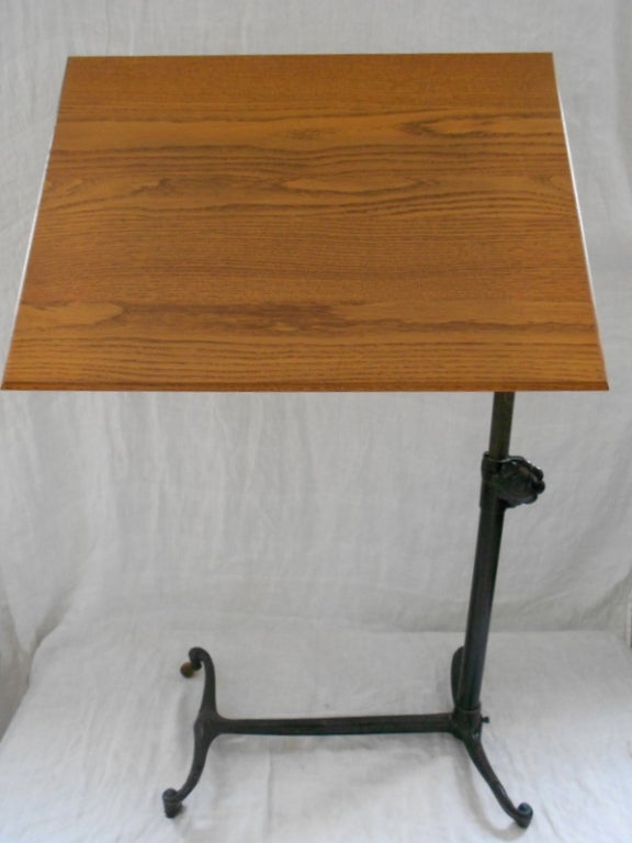 Drafting table with oak top and cast iron base on wooden wheels is around 100 years old and functions superbly in our modern lives. The stand adjusts from 23 to 39