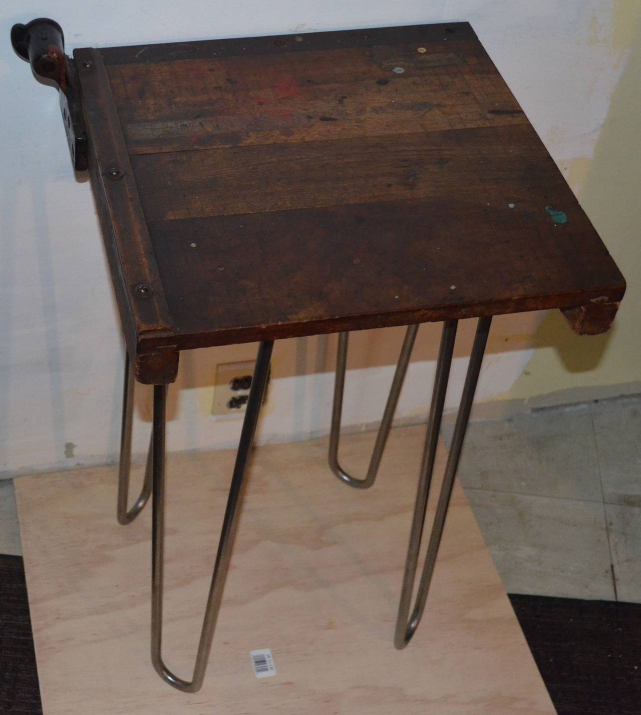 Table has been fashioned from a vintage classroom paper cutter mounted on heavy duty, stainless steel, hairpin legs. For safety purposes, the paper cutter blade has been removed leaving its cast iron mount and steel ruler intact. From years of use
