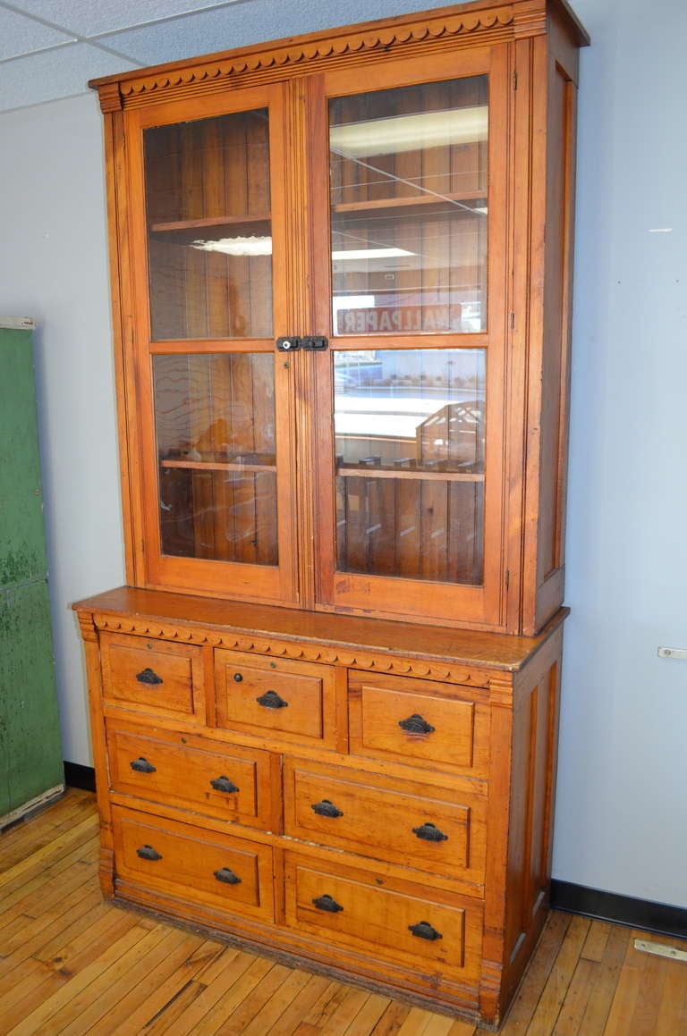 Late 1800s, American pine cabinet/buffet from midwestern general store. Scalloped trim, wainscoting back, beveled glass door fronts with original cast iron hardware. Ideal for dining room storage and dish display. Glass-doored top unit is
