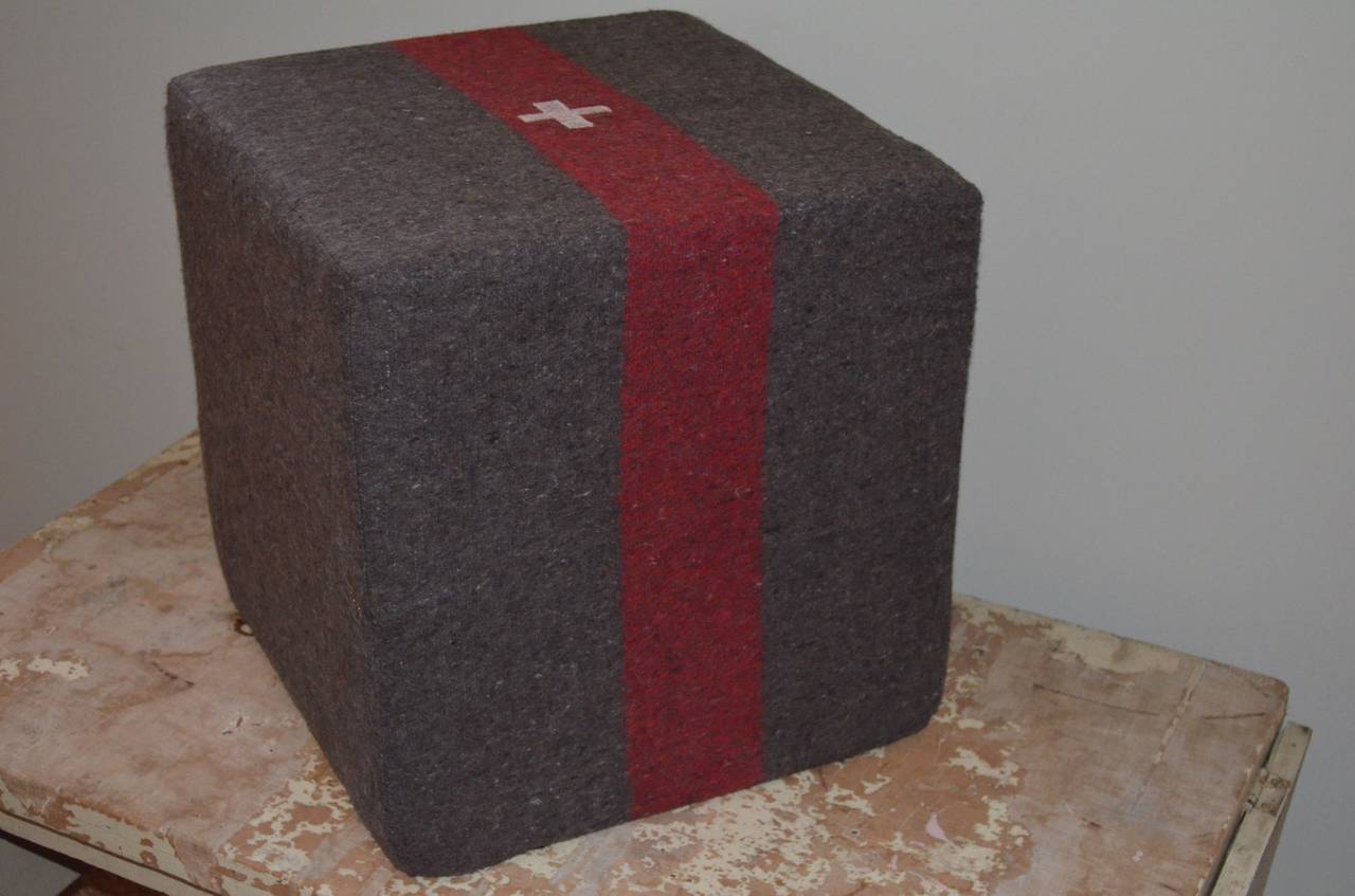 Swiss Army Blanket has been transformed into multi-functional object as pouf, ottoman, footstool, seat. This wool blanket encompasses a solid foam cube that is quite firm and can be utilized as a footrest, extra seat and decorative element. It has