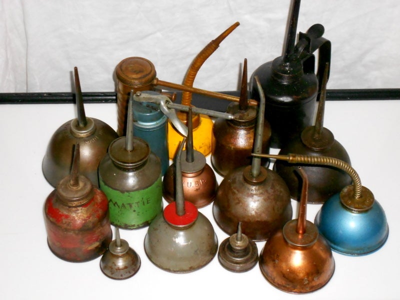 Set of vintage industrial oil cans of varied shapes and colors.