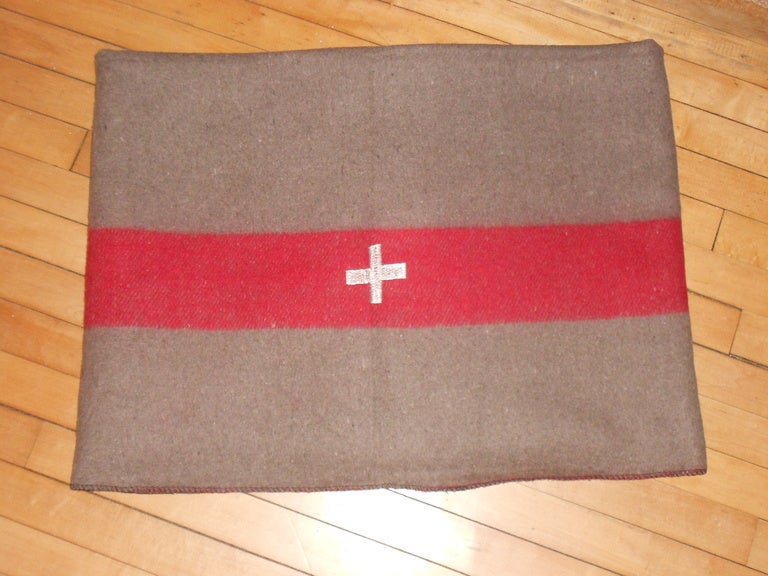 This vintage Swiss Army Blanket is part of new/old stock imported from Europe, circa 1960s. This wool blanket features the red/raspberry color bar on each end with white Swiss Cross in the center. The blanket fits a twin bed beautifully and makes a