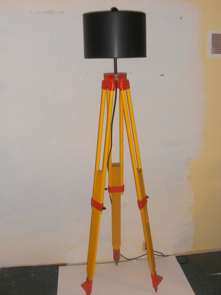 Yellow with Orange Trim Wooden Surveyor's Tripod has been transformed into an adjustable floor lamp. The legs are steel-tipped and easily adjustable in height that can range from 70