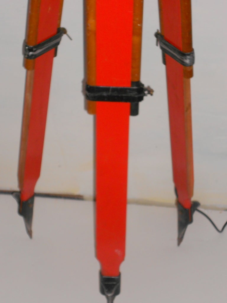 Wooden Surveyor's Tripod has been transformed into an adjustable floor lamp. The legs are painted orange wood, steel-tipped and easily adjustable in height that can range from 60