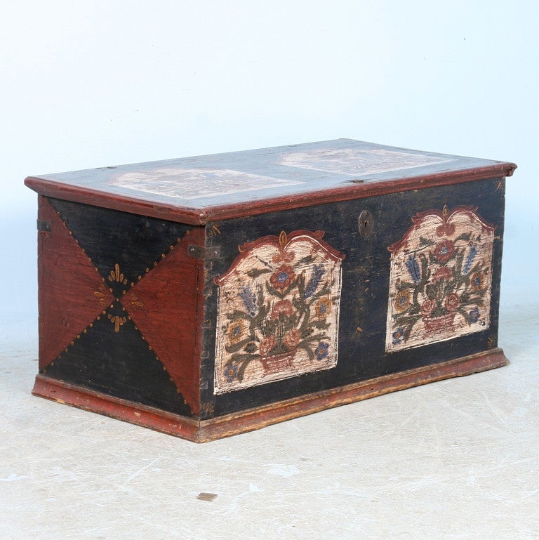 The original red and black colors are accented with a lovely floral motif on the top and front. Not the original wrought iron work and dovetail joints. The flat top allows it to be used as coffee table, at the end of a bed or simply as a beautiful