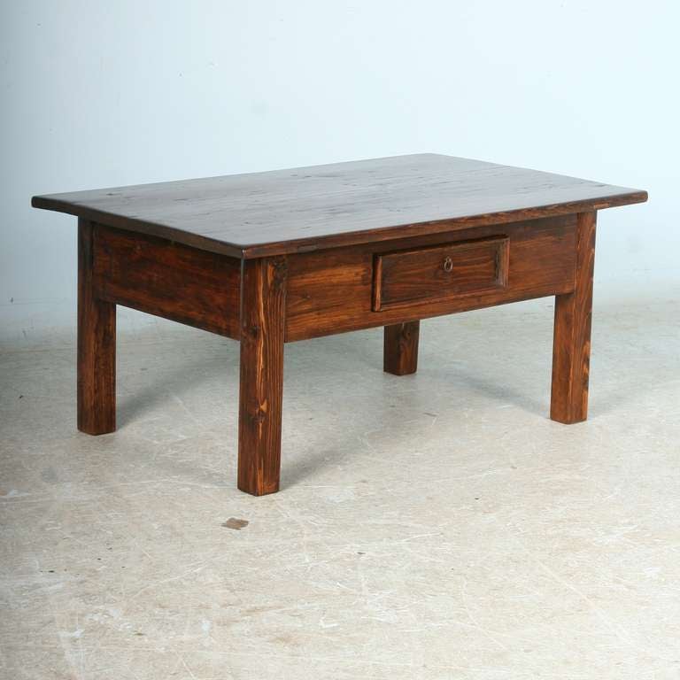 Small scale coffee table from Sweden in a dark pine finish. The single drawer add to both the look and function of the piece.