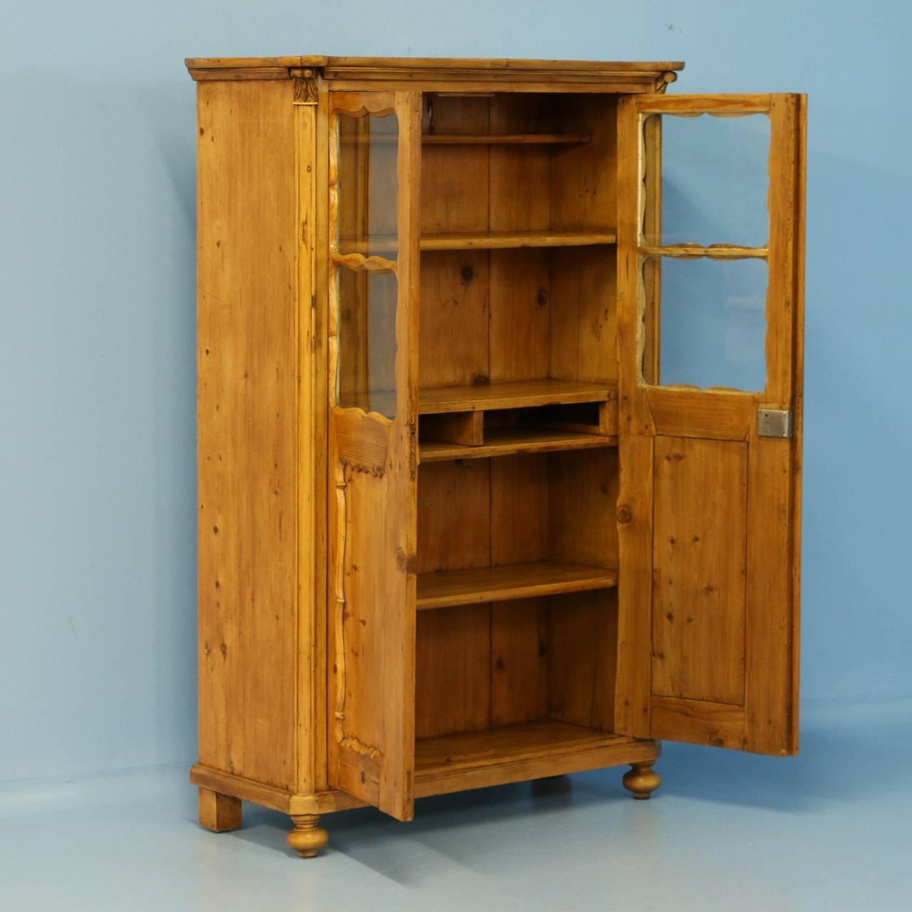 This delightful pine bookcase would have been used in a country home to store household goods and table linens originally as a cabinet. The carved, curved panels and crown add a gentle touch of grace to this sweet piece. The pine has been waxed,