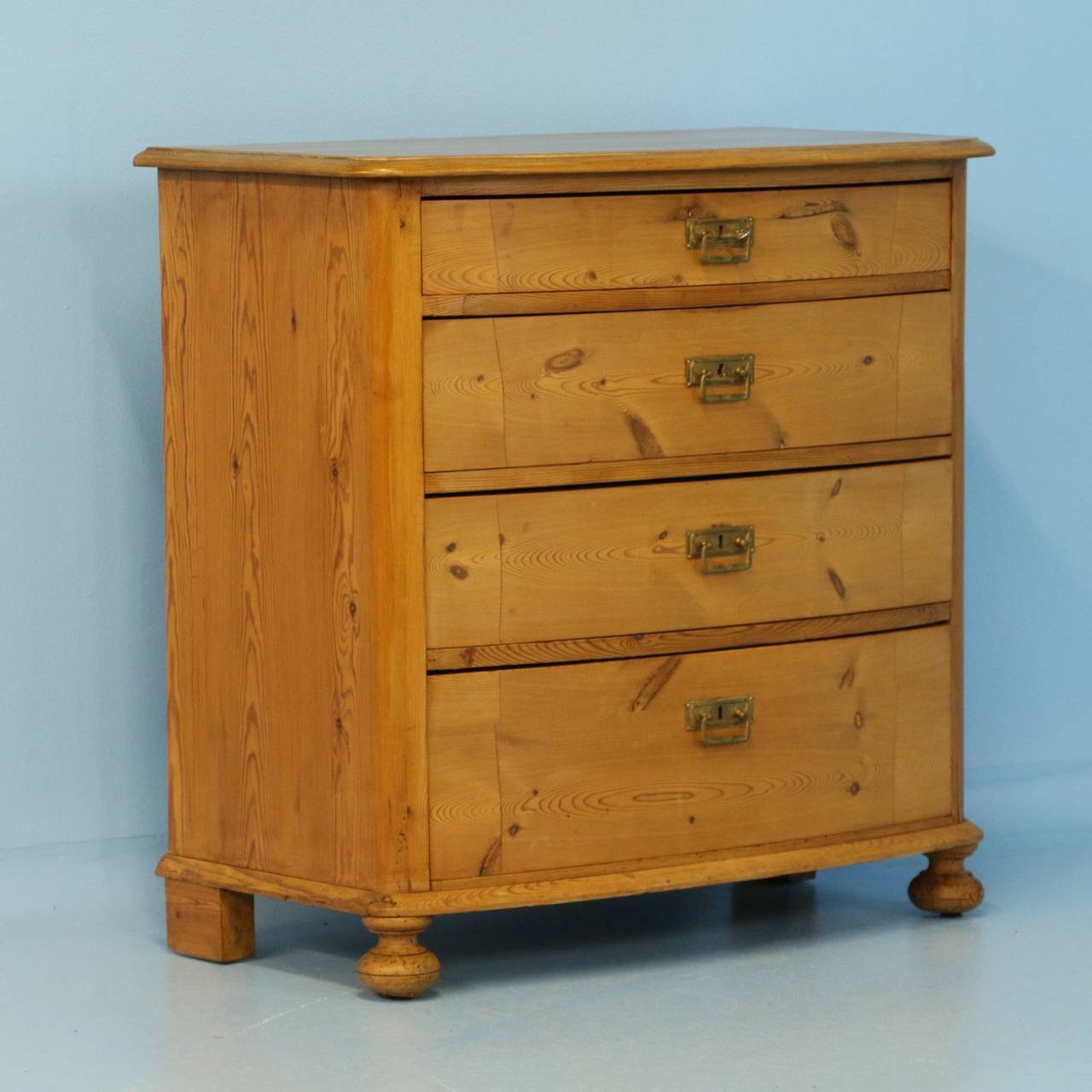 The gentle bow front of this 4-drawer chest adds to the simple grace of the piece. It has been given a waxed finish, bringing out the warmth of the wood. A pine chest of drawers such as this were typical coming of age gifts to a young woman in the
