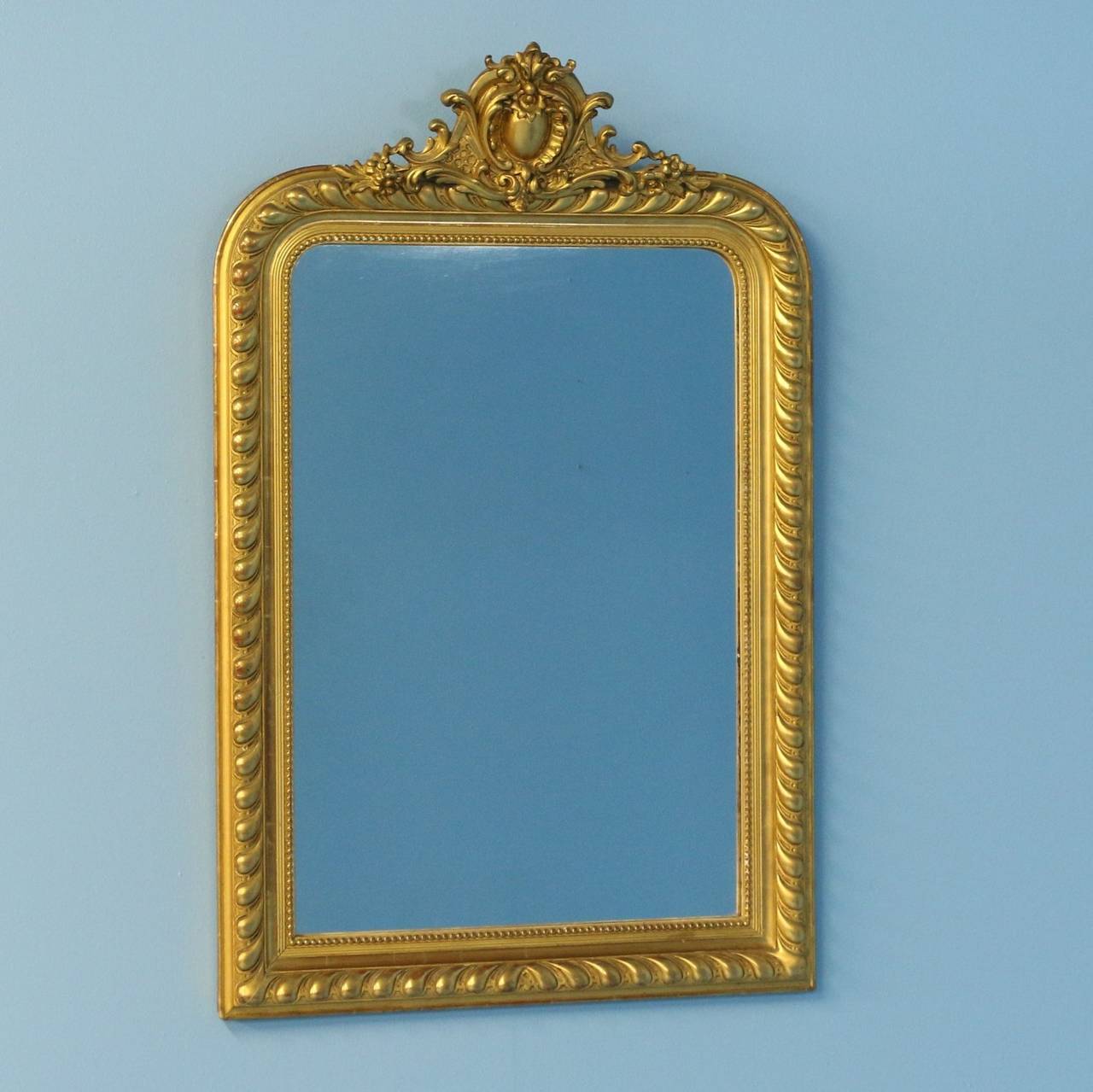 While the ornate crested pediment is elaborate, the overall visual impact is one of refined elegance in this gold gilt mirror from France.