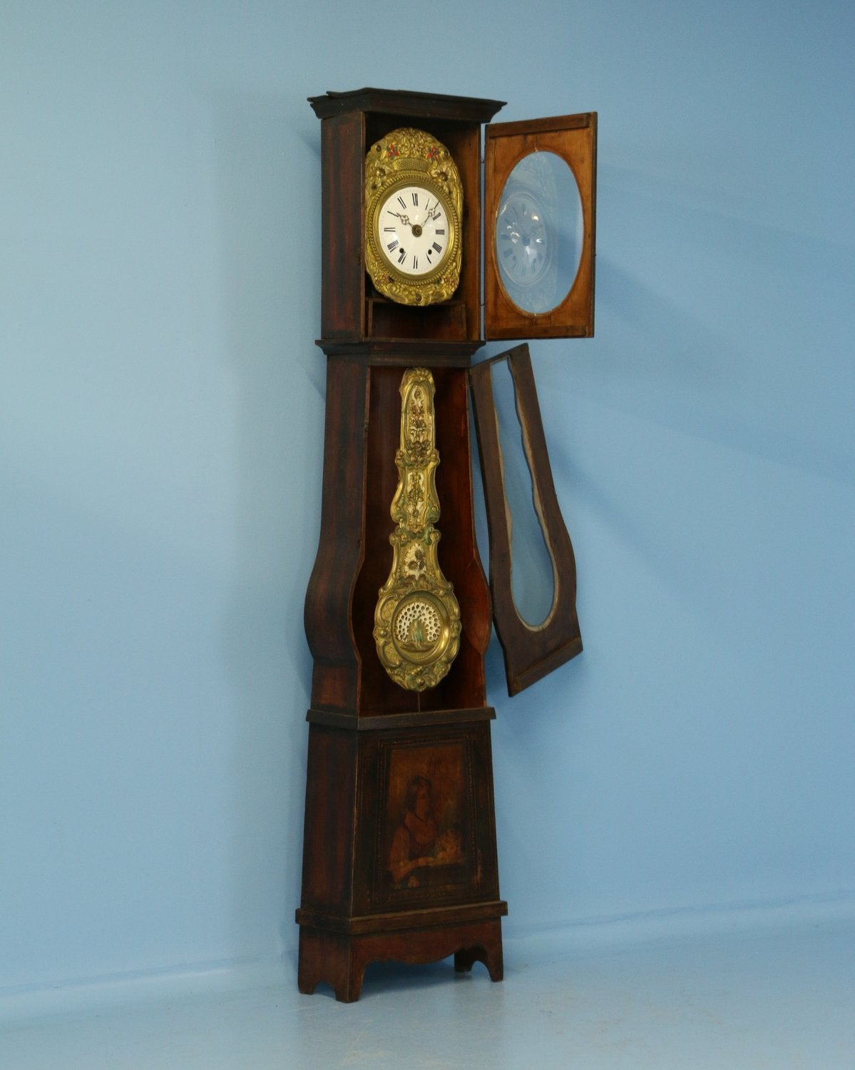 19th century French Provincial Morbier tall case clock with highly decorative pressed brass pendulum including hand-painted peacock and elaborate floral. The long case has simple painted floral and grape decoration throughout. The bottom of the