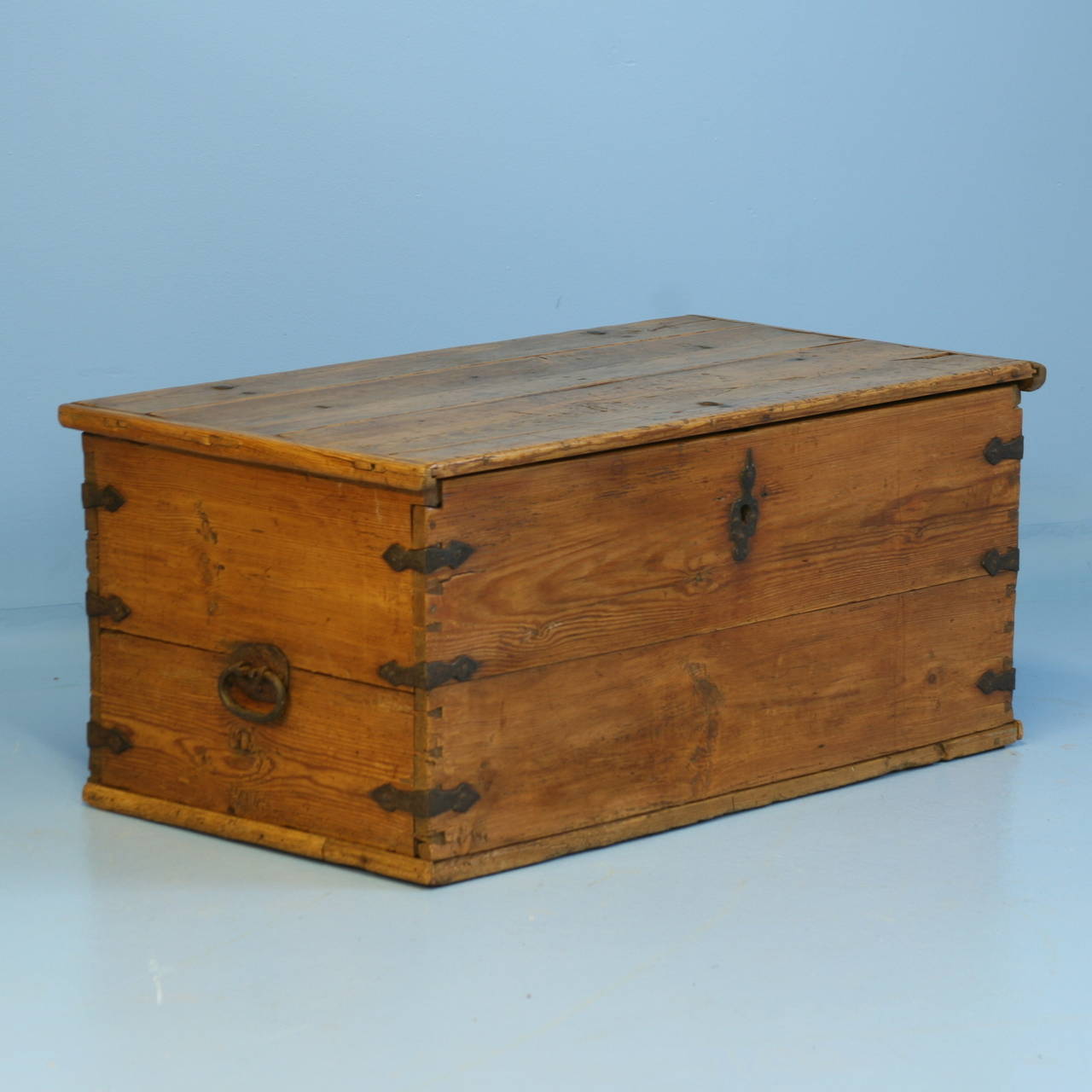 The warm patina of this pine trunk reflects the 200 years of use it has received. The hand wrought iron side handles and corners add great visual contrast against the wood.  Notice the exceptionally long hinges on the inside top. The entire trunk