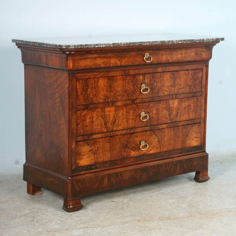 Stunning flame walnut creates the strong visual impact of this clean-lined Louis Phillipe commode/chest of 4 drawers. It is in excellent condition for its age; drawers  run smooth. The marble top is lovely; while it has one small chip on the right