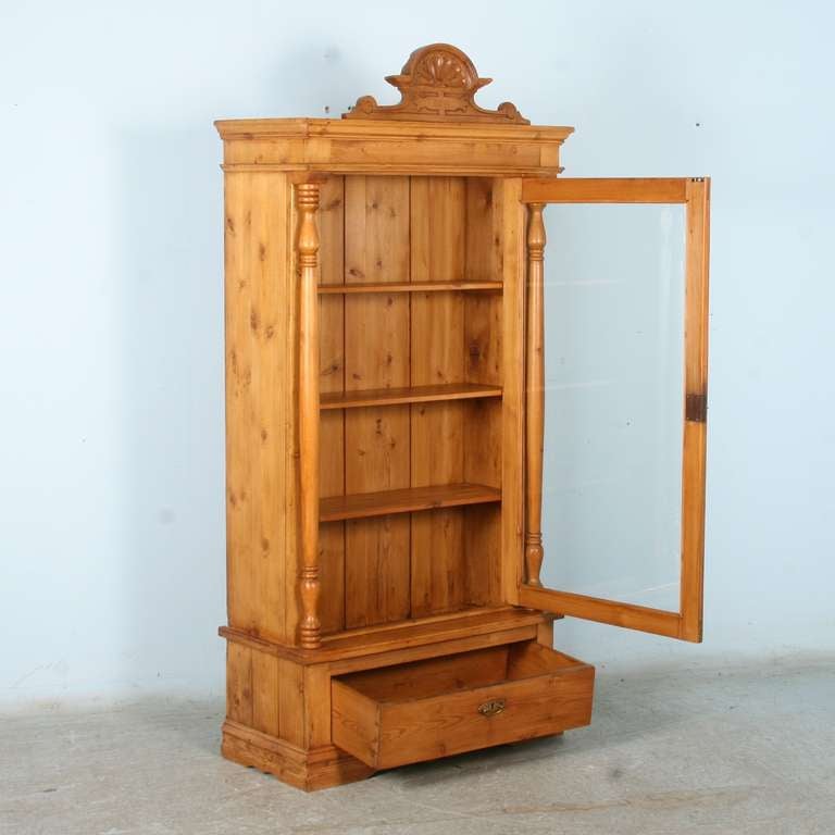 The lovely Danish pine has been given a wax finish, bringing out the warmth of the wood in this bookcase. The long turned columns flanking each side and carved bonnet add to its appeal. Overall, there is a great deal of stylish impact for the
