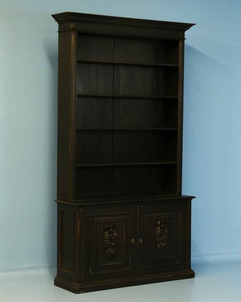 This striking bookcase has recently been given a black painted finish, bringing new life to this lovely piece. The shelves are adjustable, making this ideal to display books and other collectibles. The lower cabinet doors have lovely carved floral