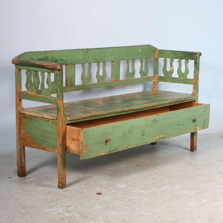 The wonderful green color of this bench is all original, as is the natural wear down to the original pine, revealed through years of use. The bench has a large pull out drawer below the seat, perfect for hidden storage.