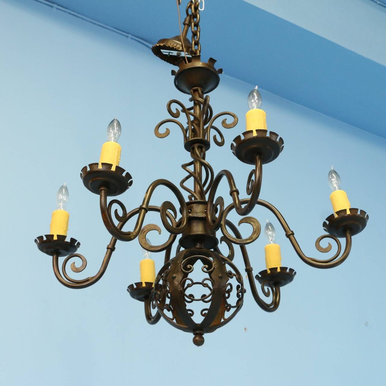 This fabulous hand-wrought iron chandelier is from the early 1900's in Denmark. Please examine the close up photos to appreciate the intricate scroll work and decorative sphere at the bottom. It has been wired for U.S. electricity and uses standard