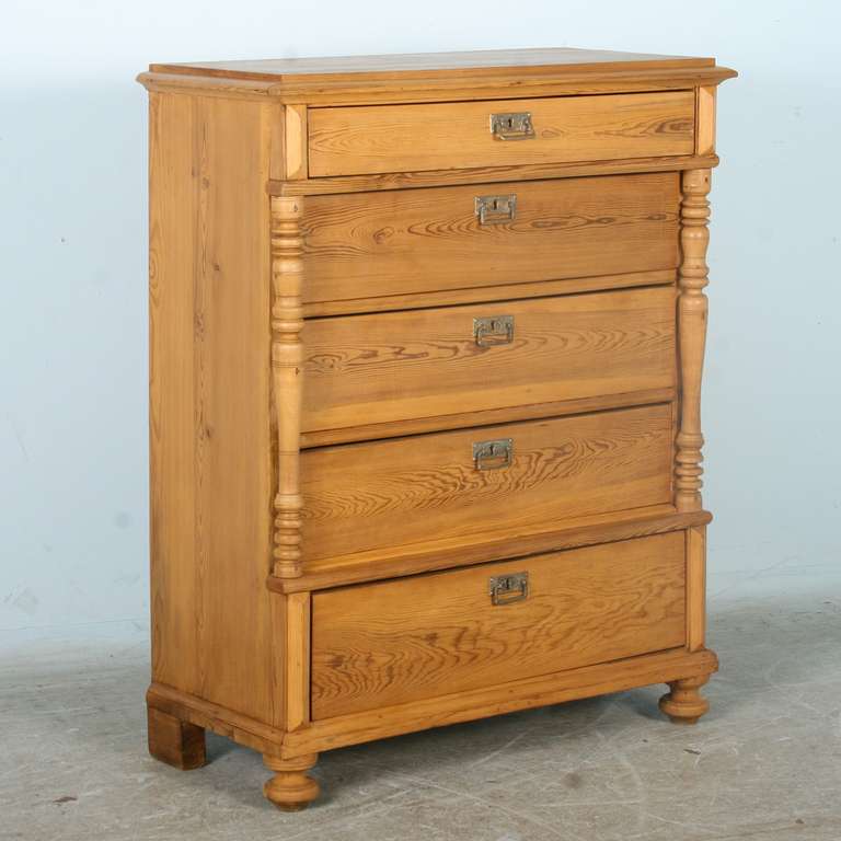 This tall pine chest of 5 drawers is from Sweden. It is in excellent restored condition. The turned columns and bun feet add dimension and character to the piece. The pine has been given a wax finish bringing out the warmth of the wood.