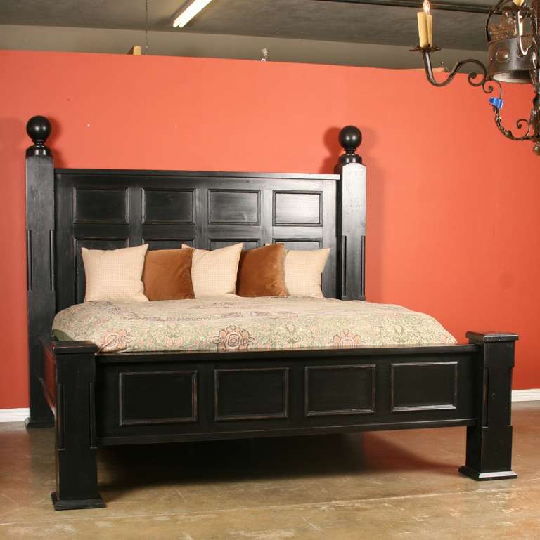 This custom king size bed is made from reclaimed antique parts dating from 1880-1910. The tall posts were originally ballusters from a grand staircase, and panels came from a mansion. It has been given a black painted finish. Please examine the