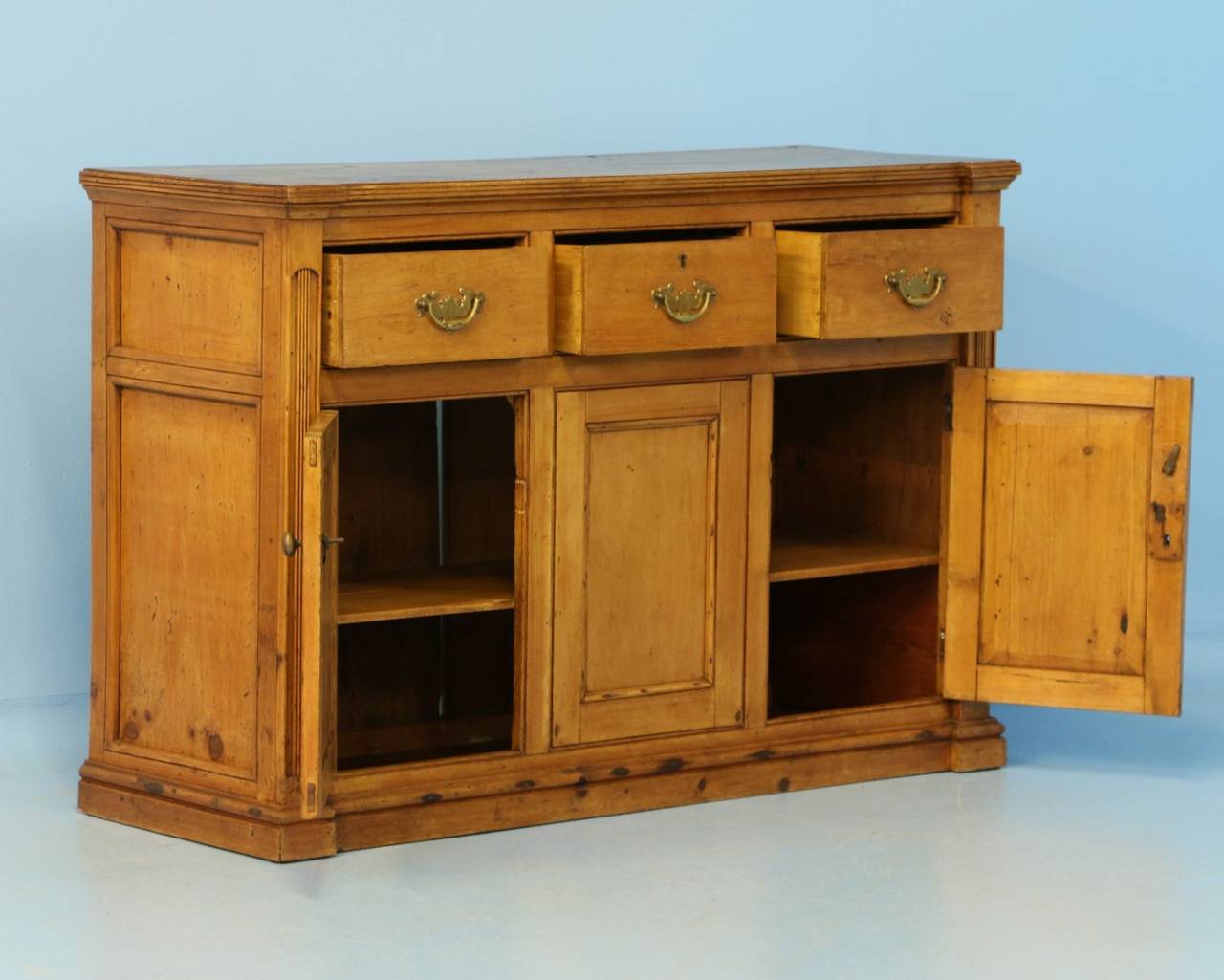 Lovely pine buffet/sideboard with 3 drawers over 2 doors. Note the simple decorative appeal of the door panels and vertical dentil molding/carving along the sides. When the doors are opened you have access to the 