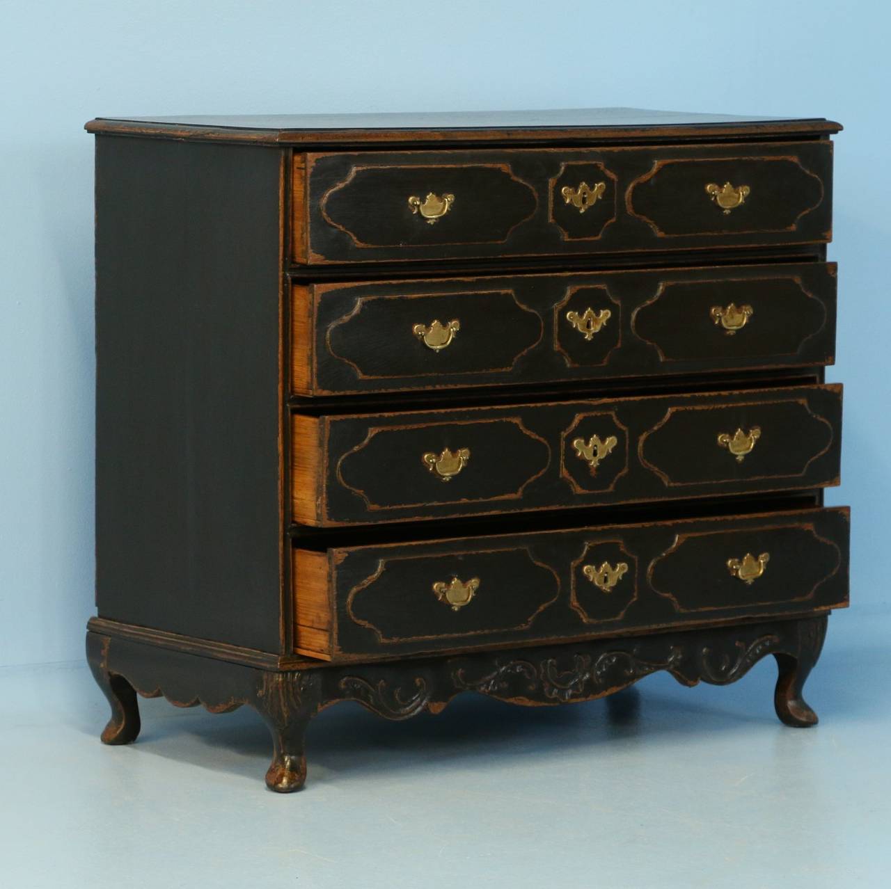 This dramatic chest of four drawers has decorative panels on each drawer that add to the visual appeal. It has recently been given a black painted finish, bringing out the dimension of the panels and lovely carving at base, adding to the overall