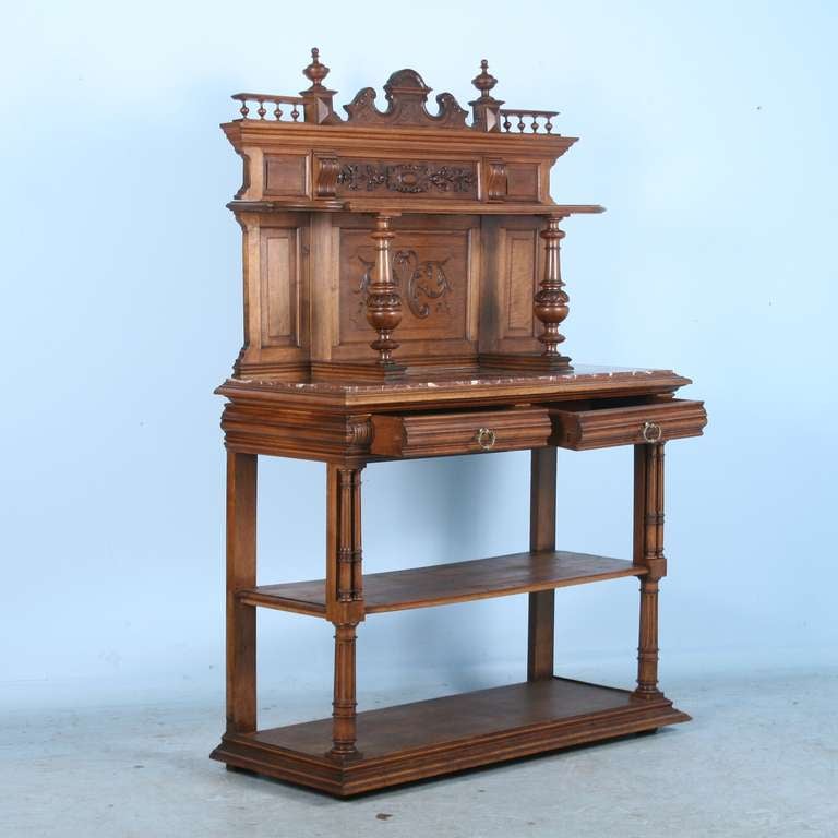 This impressive buffet server is carved with intricate floral and scrolling details, lovely turned finials and has a beautiful marble top for serving dishes. Beneath, it has two pull out drawers for serving pieces and spacious shelves below to