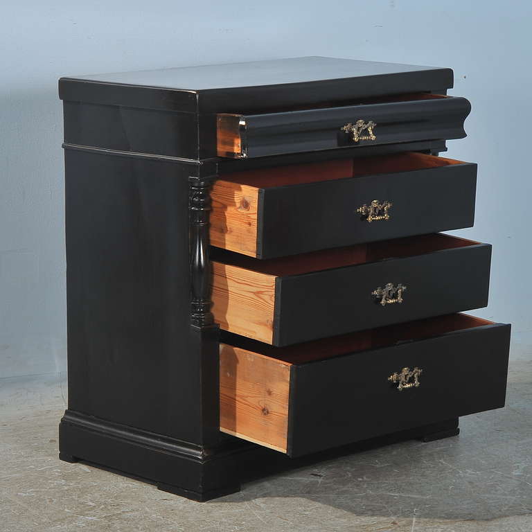 This lovely chest of drawer has turned column details and a gently curved top drawer, typical Danish styling of the late 1800's. It is pine, and has been given a new black painted finish, providing a fresh look to this old piece. The size allows it